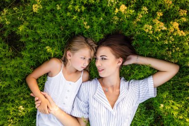 Anne ve kızının süre çiçekli çayırda yalan ve birbirine bakarak rahatlatıcı üstten görünüm