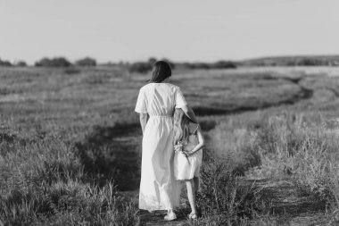 Anne ve kızı yeşil çayır kırsal karayoluyla yürüyen siyah beyaz çekim