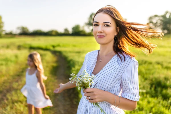 Schöne Junge Mutter Mit Feldblumen Strauß Und Kleine Tochter Verschwommen — Stockfoto