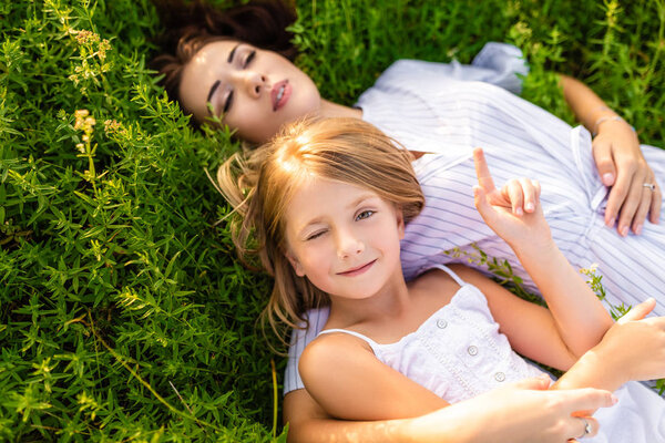 happy mother and daughter relaxing while lying in flowery meadow
