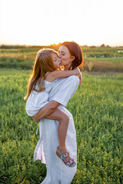 母亲和女儿在夕阳中拥抱绿色田野 — 图库照片