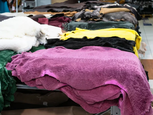 various colored sheep skins on table in leather workshop