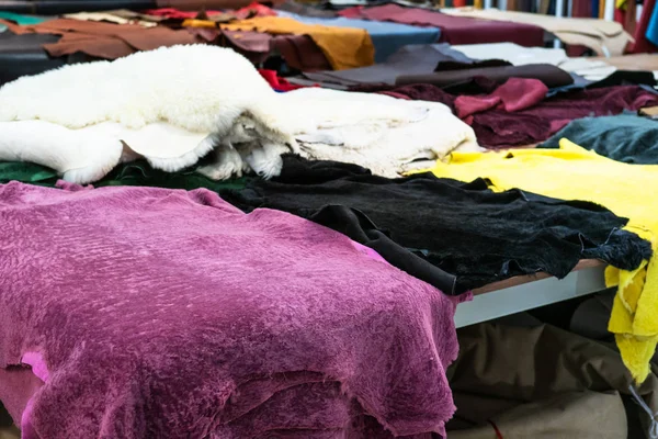 many colored sheep skins on table in leather workshop