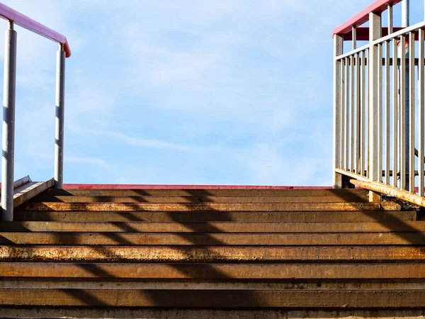 rusty steps of metal outdoor stairs to blue sky in sunny day