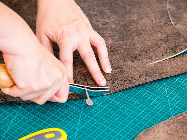 workshop of making the carved leather bag - craftsman marks pattern on the carved leather for handbag by adjustable edge creaser tool