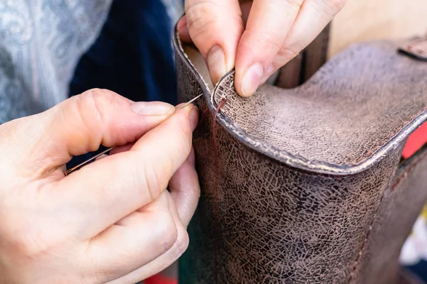 workshop of making the carved leather bag - craftsman stitches the side edge of the handbag