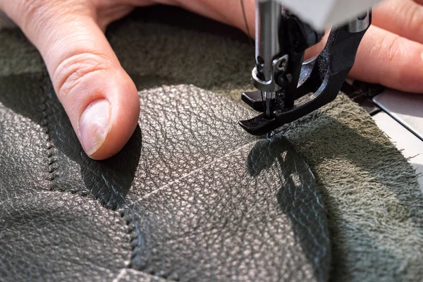 workshop of making the leather bag for jewelry - craftsman stitches pockets of pouch on sewing machine