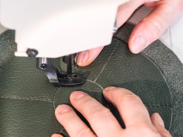 workshop of making the leather bag for jewelry - craftsman stitches the bottom of pouch on sewing machine