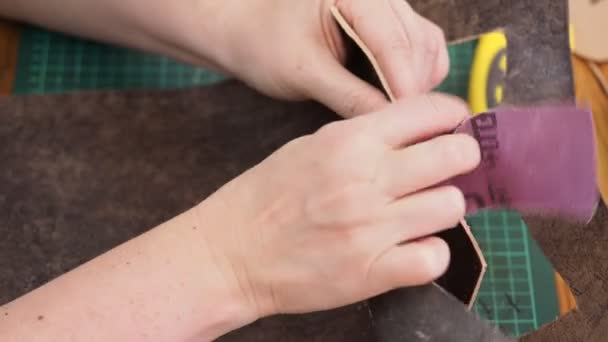 Workshop of making the carved leather bag - craftsman sands the edges of leather detail with sandpaper — Stock Footage Workshop Making Carved Leather Bag Craftsman Sands Edges Leather Detail Royalty Free Stock Footage