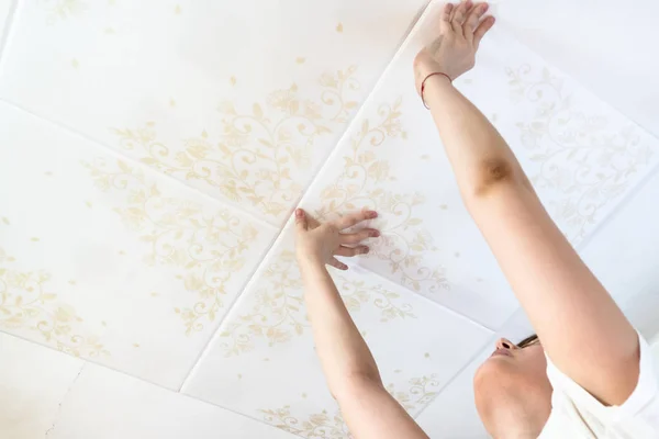 girl installing styrofoam ceiling tiles