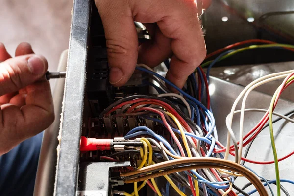 electrician disassembles electric oven during repair in home kitchen