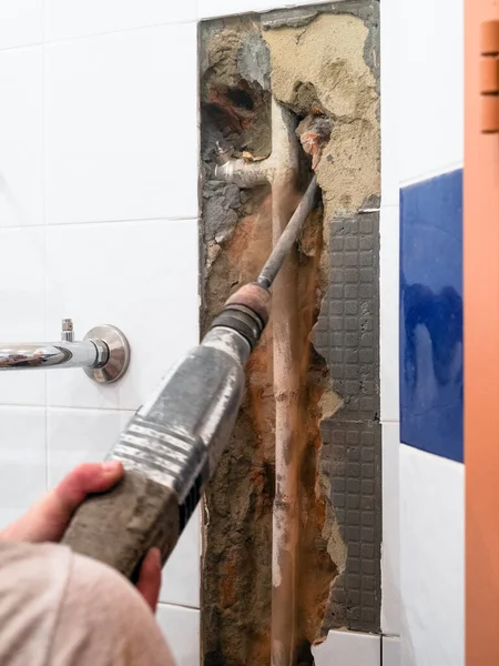 repairing of plumbing riser of heated towel rail at home - breaking wall to clean water pipe from concrete with rotary hammer