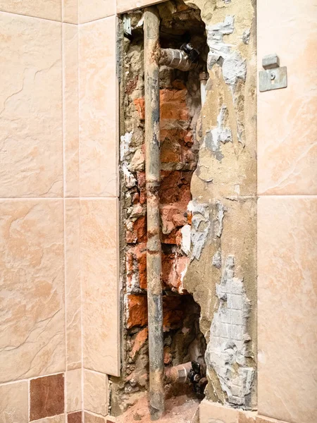 repairing of plumbing riser of heated towel rail at home - used water supply pipe in hole in wall covered by tiles