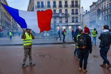 Sarı yelek (Gilets Jaunes), yakıt vergisi, hükümet ve Fransa Cumhurbaşkanı Macron karşı protesto. Bir protestocu sahnede Fransız bayrağı sallıyordum. Lyon, Fransa. 