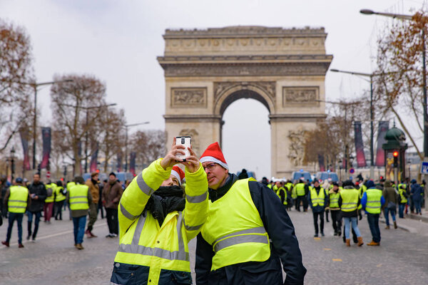 Protesters of 5th Yellow Vests demonstration (Gilets Jaunes) against fuel tax, government, and French President Macron taking selfie at Champs-Elysees, Paris, France. December 15 2018.