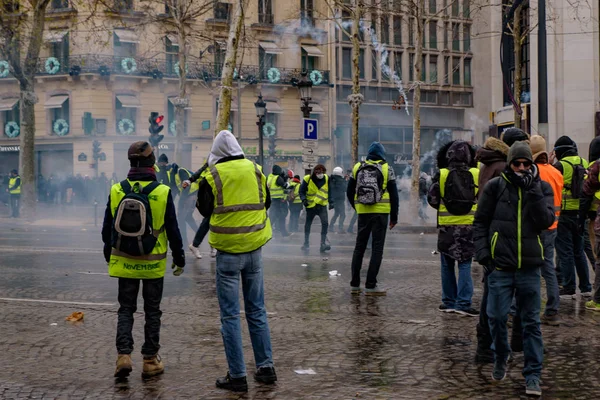 防暴警察向在法国巴黎香榭丽舍大街举行的反对燃油税 政府和法国总统马龙的黄背心示威 Gilets Jaunes 抗议者发射催泪弹 2018年12月15日 — 图库照片