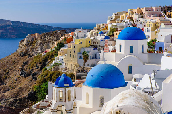 Blue domed church and traditional white houses facing Aegean Sea in Oia, Santorini, Greece