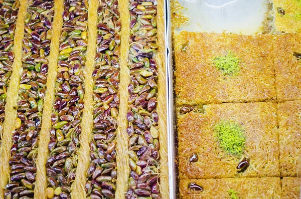 Traditional oriental dessert baklava. Middle Eastern sweetness on the street market. Turkish sweet baklava on a tray.Eastern sweets in a wide range. Arabic delight with almond, cashew pistachio nuts.