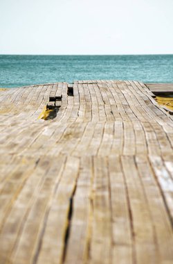 Tropikal sahildeki ahşap iskele ve mavi gökyüzü yaz arkaplanı. Tatil arka planı, kopyalama alanı. Seçici odak resmi.
