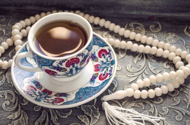 Geleneksel oryantal süs ve parlak dantel arka plan üzerinde fildişinden yapılmış hafif tespih ile bir fincan lezzetli, güçlü Türk kahvesi.