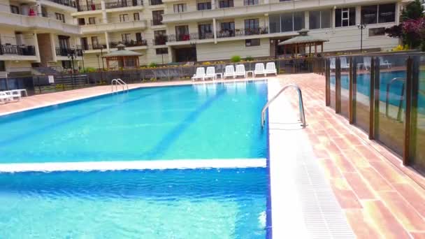 Leeg hotelzwembad onder de open lucht. Witte ligbedden zonder toeristen, vakantiegangers. — Stockvideo