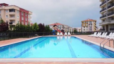 Açık gökyüzünün altında boş bir otel havuzu. Turistler ve tatilciler olmadan beyaz güneşlikler..