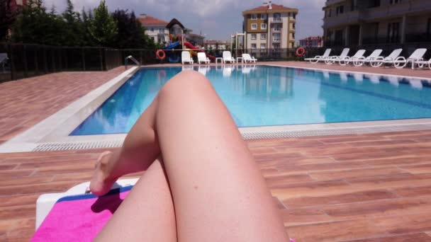 Pernas de uma jovem branca. Close-up. mulher jaz banhos de sol piscina oposta . — Vídeo de Stock