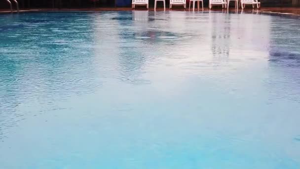 En cámara lenta. Gotas de lluvia en la superficie del agua en la piscina. Primer plano . — Vídeos de Stock