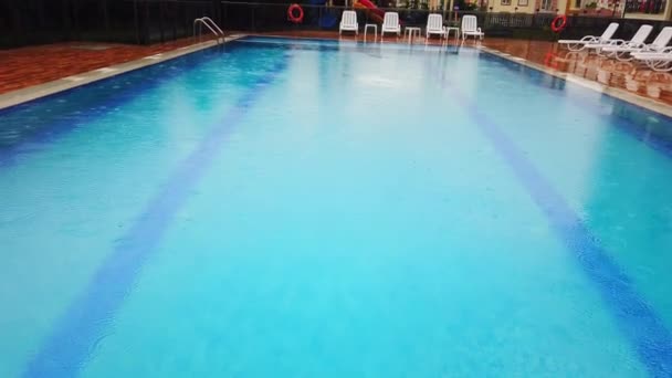 En cámara lenta. Gotas de lluvia en la superficie del agua en la piscina. Primer plano . — Vídeos de Stock