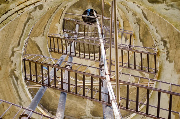 Terk edilmiş pompa istasyonu. Çimento ve ahşaptan yapılmış su kulesi, metal merdivenler ve parmaklıklar. Sarmal merdivenlerden aşağı. Birkaç yağmur yağan sanat eğrisi merdivenleri. Odak resmini seç.