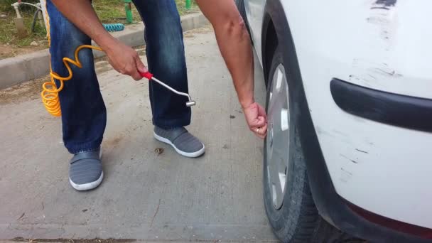 Homme balançant roues, pneus de voiture de tourisme avec air comprimé à la station service. — Video