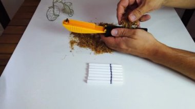 Ev yapımı sigara. Yakın plan. Adam boş sigara kutularını tütünle dolduruyor.