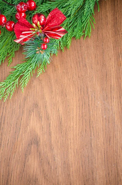 Green spruce branches. Brown wooden background. White, red, multi-colored Christmas toys. Decorations for Christmas tree made of wood and ceramics. Festive fun concept. Congratulatory backdrop.