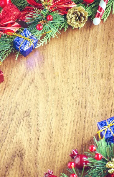 Yeşil ladin dalları. Kahverengi ahşap arka plan. Beyaz, kırmızı, çok renkli Noel oyuncakları. Ahşap ve seramiklerden yapılmış Noel ağacı süslemeleri. Şenlikli eğlence konsepti. Tebrik arkaplanı. 