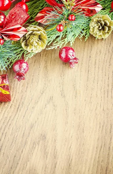 Yeşil ladin dalları. Kahverengi ahşap arka plan. Beyaz, kırmızı, çok renkli Noel oyuncakları. Ahşap ve seramiklerden yapılmış Noel ağacı süslemeleri. Şenlikli eğlence konsepti. Tebrik arkaplanı. 