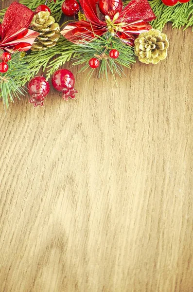 Yeşil ladin dalları. Kahverengi ahşap arka plan. Beyaz, kırmızı, çok renkli Noel oyuncakları. Ahşap ve seramiklerden yapılmış Noel ağacı süslemeleri. Şenlikli eğlence konsepti. Tebrik arkaplanı. 