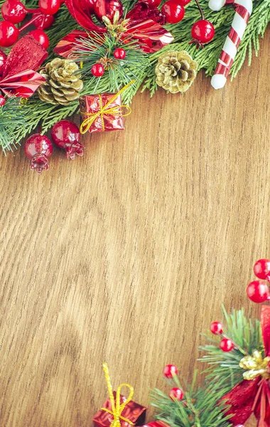 Yeşil ladin dalları. Kahverengi ahşap arka plan. Beyaz, kırmızı, çok renkli Noel oyuncakları. Ahşap ve seramiklerden yapılmış Noel ağacı süslemeleri. Şenlikli eğlence konsepti. Tebrik arkaplanı. 