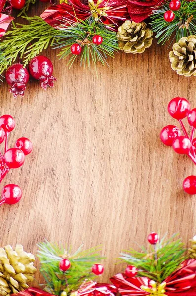 Yeşil ladin dalları. Kahverengi ahşap arka plan. Beyaz, kırmızı, çok renkli Noel oyuncakları. Ahşap ve seramiklerden yapılmış Noel ağacı süslemeleri. Şenlikli eğlence konsepti. Tebrik arkaplanı. 