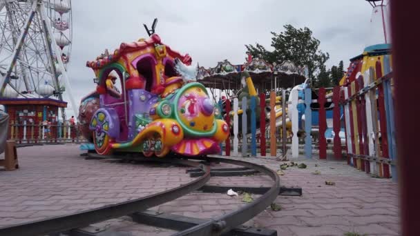 Brilhante, colorido, passeio de trem infantil em trilhos de metal. parque de diversões das crianças — Vídeo de Stock