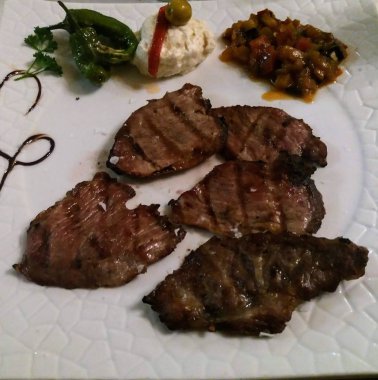 Kavrulmuş sebze ile beyaz plaka üzerinde sulu sığır filetosu