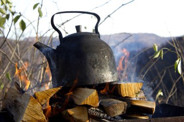 Kamp ve bir adam bir yangın bir kazan ve bitkisel çay pişirme. Bir adam doğada yiyecek bir kazan açık bir günde üzerinde hazırlar. Bir piknik bir su ısıtıcısı ve bir kazan bir yangın sırasında gıda. 