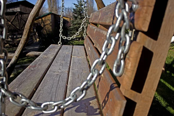 The element of the metal chain, as a decoration to the swings in the territory of the house for the rest. Metal chain on the street swing in the background of the cottage for tourists.
