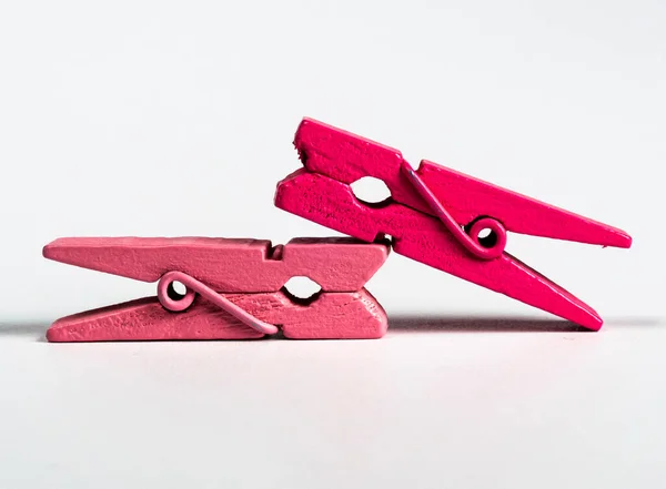İzole edilmiş beyaz arka planda dekorasyon için birbiri ardına iki pembe tahta klips tutulur. 
