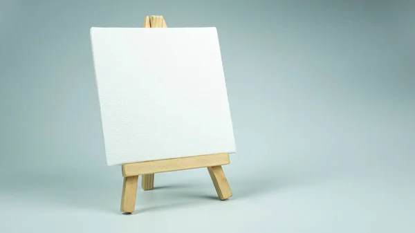 Küçük ahşap bir sehpada beyaz mini bir tuval.  