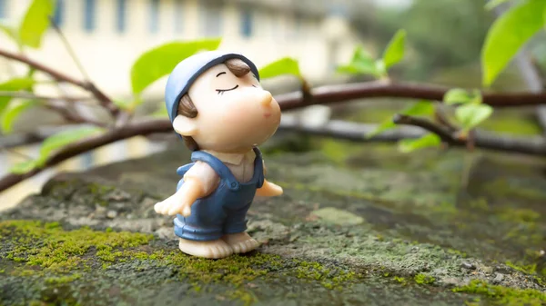 Nemli bir yüzeyde duran sevimli bir çocuk ve arkasında yeşil bir bitki. 