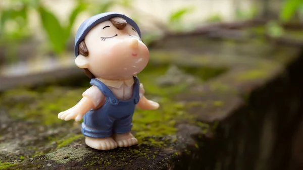 Nemli bir yüzeyde duran sevimli bir çocuk ve arkasında yeşil bir bitki. 