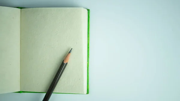 Beyaz zemin üzerinde kalem bulunan el yapımı kağıt defterin üst görünümü