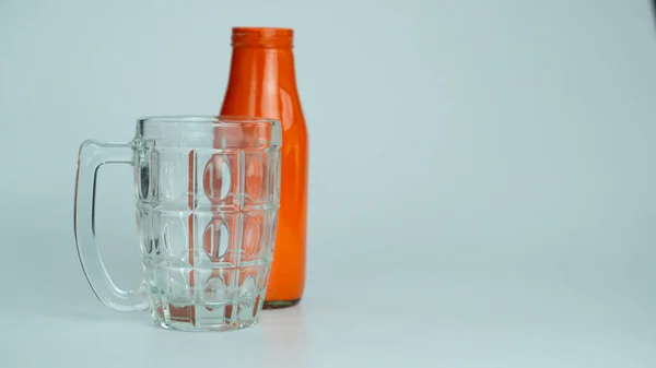 Yanında portakal şişesi olan berrak bardak suyu bardağı. 