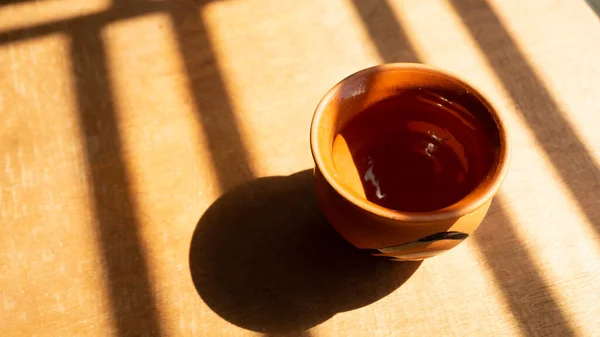 Boş çay fincanı soyut gölgeli bir kontrplak üzerinde tutulur. 