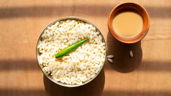 Çelik bir kasede taze çay ve ahşap bir masanın üstünde yeşil bir biber. 